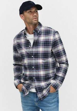 Heren flanellen overhemd in donkerblauw, wit en bordeaux geruit patroon. Button-down kraag, lange mouwen, gecombineerd met een eenvoudig wit T-shirt eronder.