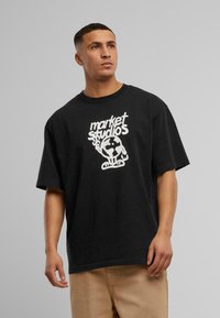 Sort oversized t-shirt med et hvidt grafisk print af "market studios" med et illustreret globusdesign på forsiden. Lavet af bomuldsmateriale.