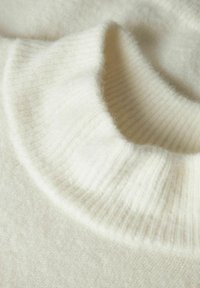 Kreemikas pullover paksu, soonilise kaelusega disainiga. Pehme, udune tekstuur ja sile kangapind.