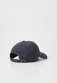 Marineblauwe katoenen baseballpet met een gebogen rand, verstelbare strap aan de achterkant en een gestructureerde afwerking. Bevat ventilatie-openingen.