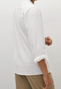 Witte linnen shirt met driekwartmouwen, opgerolde manchetten en een ontspannen pasvorm. De stof heeft een gladde textuur. De achterkant toont de kraag en naden.