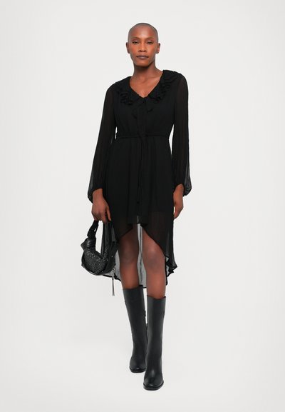 Rochie lungă neagră cu mâneci lungi, guler fronsat, talie strânsă, material transparent și hem hi-low. Asortată cu cizme negre până la genunchi și o geantă texturată.