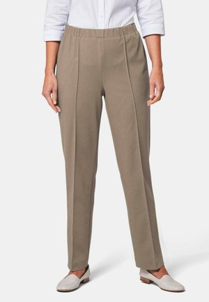 Pantalons beige à taille élastique avec une finition texturée, dotés de deux plis à l'avant et d'une coupe droite, associés à des chaussures blanches à enfiler.