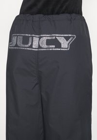 Melni, viegli bikses ar elastīgu jostu, ar lielu, spīdošu rhinestone "JUICY" logotipu aizmugurē.