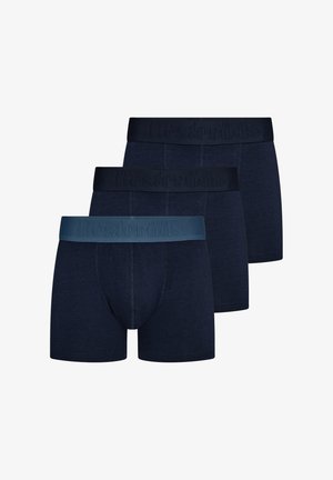 Drie paar donkerblauwe herenboxershorts met elastische taillebanden in verschillende tinten blauw, overlappend gerangschikt op een witte achtergrond.