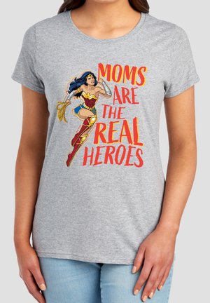 Gray t-shirt with a graphic of Wonder Woman and text "Moms are the real heroes" worn by a person with light skin and blue jeans.