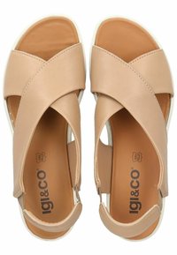 Sandali in pelle beige con design a fascia incrociata, punta aperta e dettagli elastici. Soletta ammortizzata con suola in gomma bianca. Logo del marchio visibile.