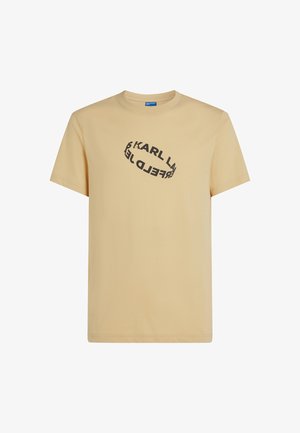 Kratka bež majica iz bombaža s kratkimi rokavi, na sprednji strani z grafičnim besedilom v črni ovalni obliki. Klasičen ovratnik.