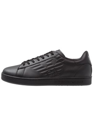 Sort lavtopet lædersneaker med præget logo på siden, sorte snørebånd og flad sål, vist i sideprofil på hvid baggrund.