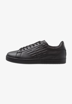 Czarny niski skórzany sneaker z wytłoczonym logo po boku, czarne sznurowadła i płaska podeszwa, pokazany z profilu na białym tle.