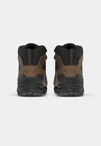 Las botas de senderismo en negro y marrón presentan un diseño resistente, materiales impermeables y una suela de goma texturizada con soporte para los tobillos y un sistema de cordones.