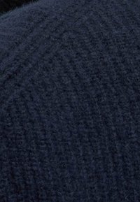 Ciężkie niebieskie wełniane tkaniny z fakturowanym, prążkowanym wzorem. Materiał wydaje się miękki i ciepły, z delikatnymi tonalnymi wariacjami.