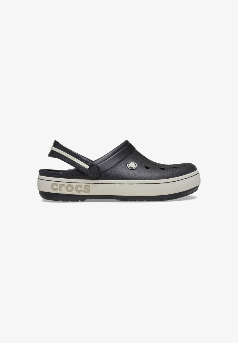 Sabot Crocs noir et blanc avec des trous de ventilation, une bride de talon réglable et un détail de marque sur le côté de la semelle, sur fond blanc.