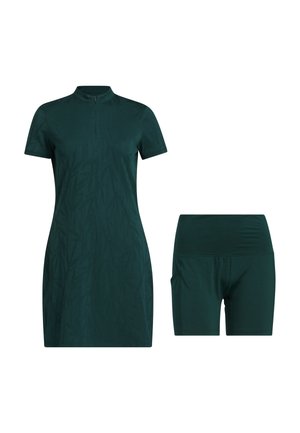 Tvådelad träningsklädset bestående av en mörkgrön kortärmad klänning med dragkedja i halsen och matchande shorts. Tyget är glatt med en subtil textur.