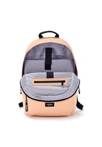 Zaino color pesca chiaro con pattina grigia, scomparto interno e accessori neri. Presenta una tasca con zip sulla parte anteriore e spallacci regolabili.