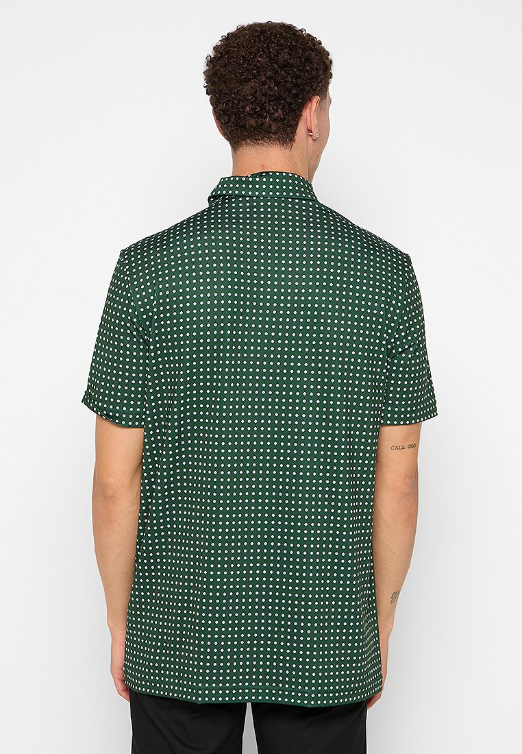 Camisa de manga corta en verde oscuro con lunares blancos. Tejido ligero, cuello estándar y un corte relajado. Presenta un dobladillo recto.