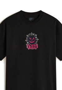 Camiseta de algodón negra con un estampado gráfico de una criatura sonriente con picos en rojo y negro, con el texto "Vans" debajo. Mangas cortas.