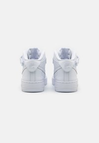 Biele kožené tenisky Nike Air s vysokým strihom, ktoré majú polstrovaný golier, textúrované podrážky a akcenty loga na päte.