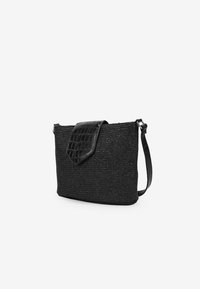 Bolso de mano negro tejido con una solapa de faux cuero negro texturizado y brillante, y una correa ajustable. Forma rectangular, diseño minimalista.