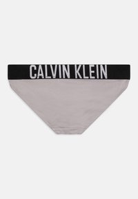 Slip grigio Calvin Klein con cinturino elastico nero caratterizzato da testo logo bianco, texture liscia e design classico.