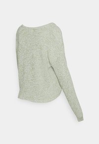 Sweater em malha verde-claro com uma textura suave, apresentando um decote redondo, uma manga longa de um lado e uma bainha ligeiramente curva.