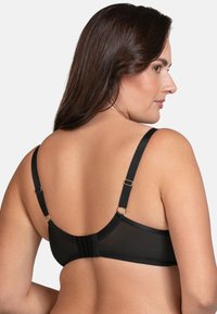 Black bra with smooth fabric, adjustable straps, and hook-and-eye back closure. Features a minimalist design and soft texture.