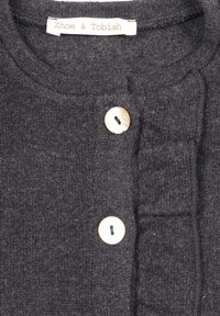Maglione grigio scuro in maglia con scollatura rotonda, chiusura con bottoni e una texture morbida, con un'etichetta che recita "Zhoe & Tobiah."