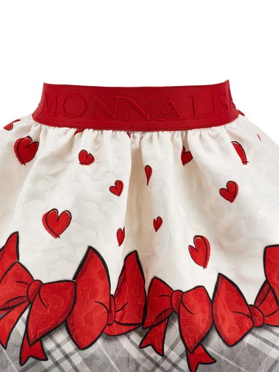 Section de jupe blanche avec motif de cœurs rouges et de nœuds rouges, avec une ceinture rouge brodée du mot "MONNALISA."