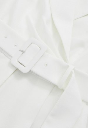 Balts audums ar gludu tekstūru, kam ir josta ar taisnstūrveida baltu sprādzi, aizdarināta ar sudraba detaļām, un salocītu drapējuma detaļu.