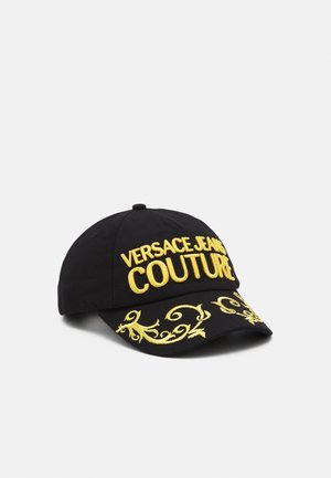 Czarna czapka bejsbolowa z żółtym napisem „VERSACE JEANS COUTURE” i ozdobnymi żółtymi haftami na daszku, pokazana na białym tle.