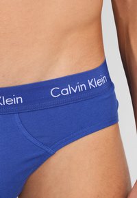 Calvin Klein blaue Boxer Shorts aus weichem Stoff mit einem gerippten Bund, auf dem das "Calvin Klein"-Logo in Weiß zu sehen ist.