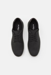 Chaussures noires à lacets en matière lisse, avec un bout rond et une semelle en caoutchouc blanche contrastante. Marque "ALDO" apposée sur la semelle intérieure.