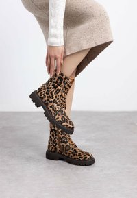 Botines de leopardo con tejido texturizado, suela de goma negra, diseño de cordones y cremallera lateral para un fácil acceso.