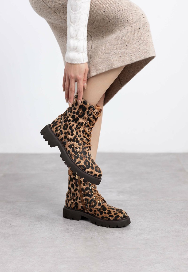 Botines de leopardo con tejido texturizado, suela de goma negra, diseño de cordones y cremallera lateral para un fácil acceso.