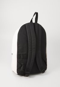 Schwarz-weißer Rucksack mit doppelten Trägern, strukturiertem Stoff und rundem Design. Verfügt über verstellbare Riemen und verstärkte Nähte.