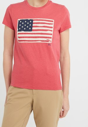 T-shirt in cotone rosso con motivo stampato della bandiera americana. Collo rotondo, maniche corte e una vestibilità ampia con una leggera texture.