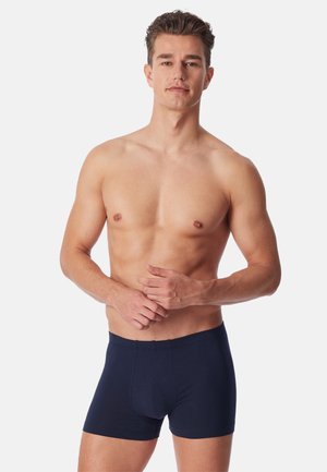 Navy blå boxershorts lavet af blødt stof, med et skræddersyet fit og ingen synlig branding. Glat tekstur med en enkel elastisk talje.