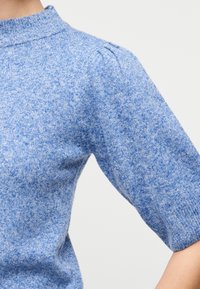 Pull en tricot bleu chiné avec manches courtes bouffantes et col montant côtelé.