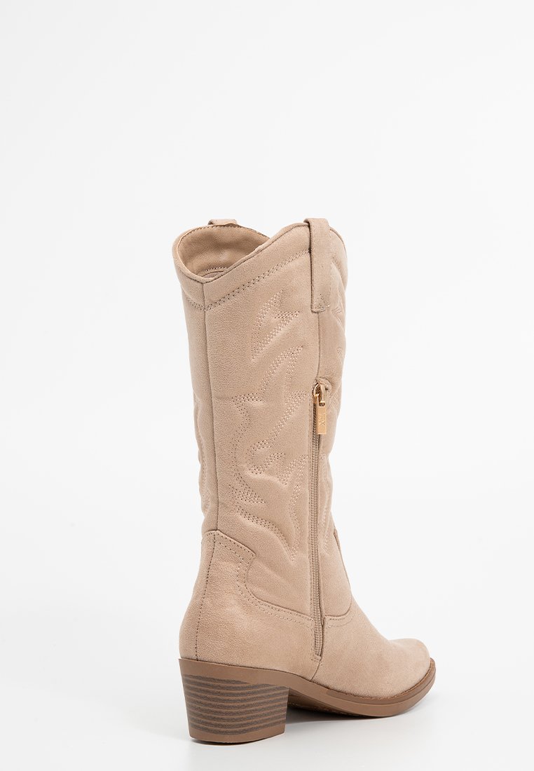 Bota de vaquero de ante beige con diseño floral bordado, cierre de cremallera lateral y tacón apilado. Textura suave con punta redonda.