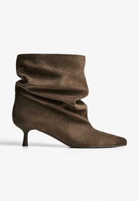 Stivaletto alla caviglia in suede marrone dal design morbido, punta affusolata e tacco a stiletto. Texture liscia e silhouette minimalista.