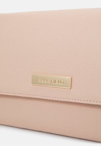 Portefeuille synthétique rose avec une finition texturée, doté d'une plaque logo en métal doré. Comprend des accents cousus et un design avec rabat horizontal.
