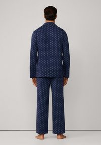 Conjunto de pijama azul marino con un sutil patrón de estrellas, compuesto por una camiseta de botón de manga larga y pantalones holgados a juego. Textura de tela suave.