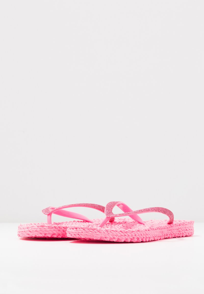 Pair of bright pink flip-flops with textured soles and glittery straps on a plain white background.