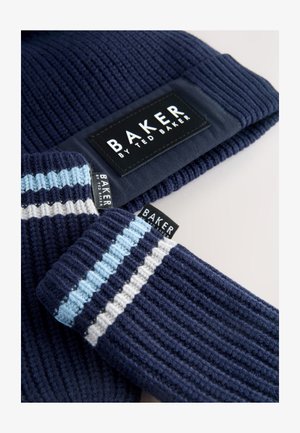 Marineblå strikket hue med ribbet tekstur og et sort mærke. Matchende ribstrikkede handsker har blå og hvide striber og sorte mærker.
