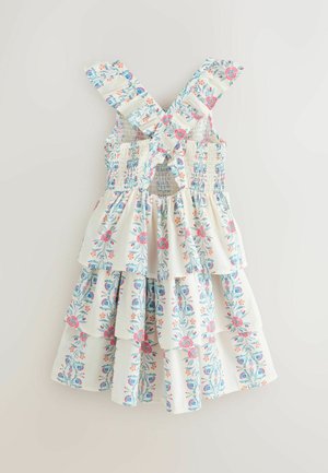 Mouwloze witte zomerjurk met gekruiste gerimpelde bandjes, gelaagde rok en een bloemenpatroon in blauw, roze en oranje.