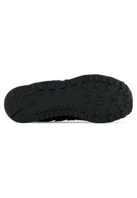 Semelle de chaussure de sport noire en matériau en caoutchouc texturé, avec des profondeurs de crans, un design non marquant et de petites particules éparpillées.