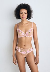 Komplet spodnjega perila iz gola mrežaste tkanine s poudarjenim rožnatim vezenjem; bralette ima nastavljive naramnice in rožne dodatke, usklajeni tangici s podobnim dizajnom.
