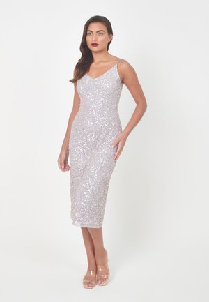 Sleeveless, silver sequined dress with a fitted silhouette, midi length, v-neckline, paired with clear heeled sandals.
