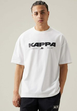 T-shirt Kappa bianco con un grande logo nero, vestibilità ampia e maniche corte. Tessuto morbido con scollatura rotonda e spalle scese.