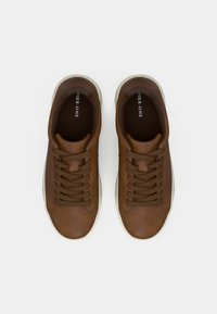 Sneakers din piele maro cu vârf rotunjit, superior texturat, închidere cu dantelă maro și talpă din cauciuc deschis. Branding vizibil pe interior.